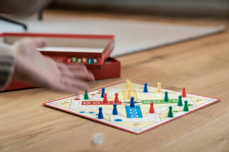 Close-up of a Ludo game with colorful pieces on a wooden floor with selective focus.